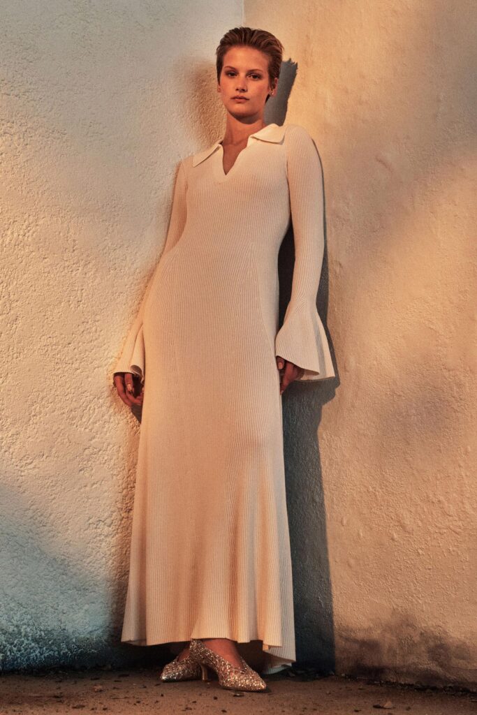 A fitted cream long-sleeve dress with a V-neckline and flared silhouette.