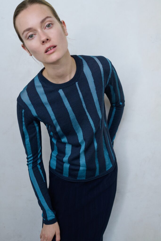 A fitted blue striped long-sleeve top paired with a navy skirt for a chic look.
