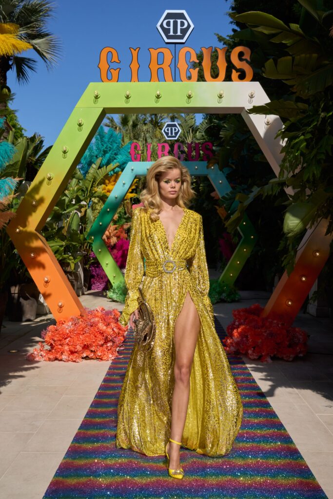 A fitted yellow silk dress with long sleeves, a V-neckline, and a dramatic slit.