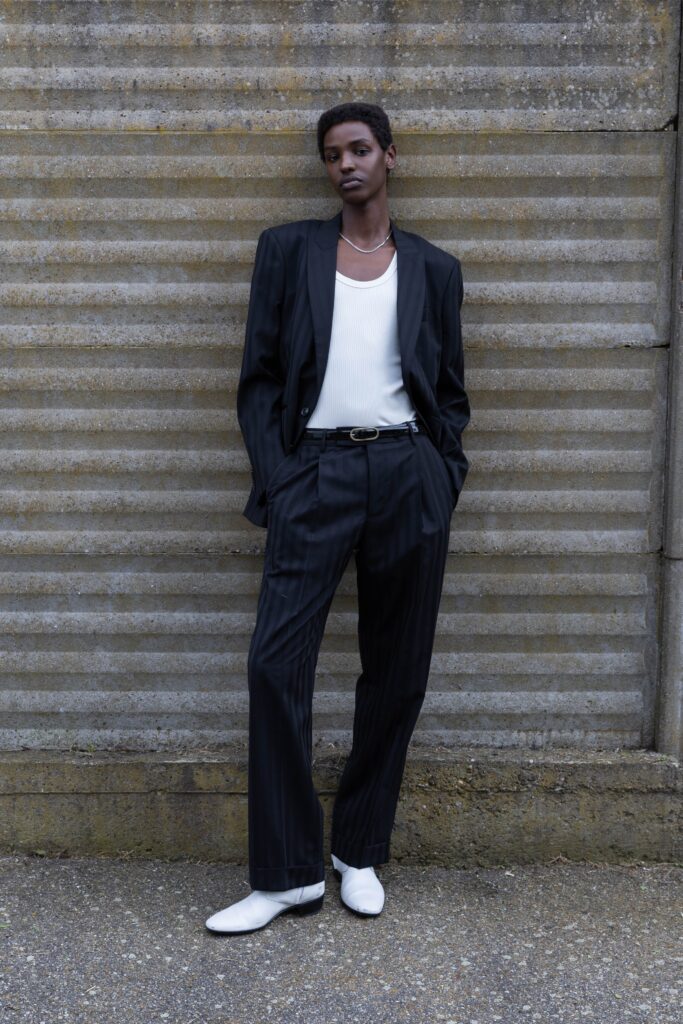 A tailored black striped suit with a collared long-sleeve shirt.