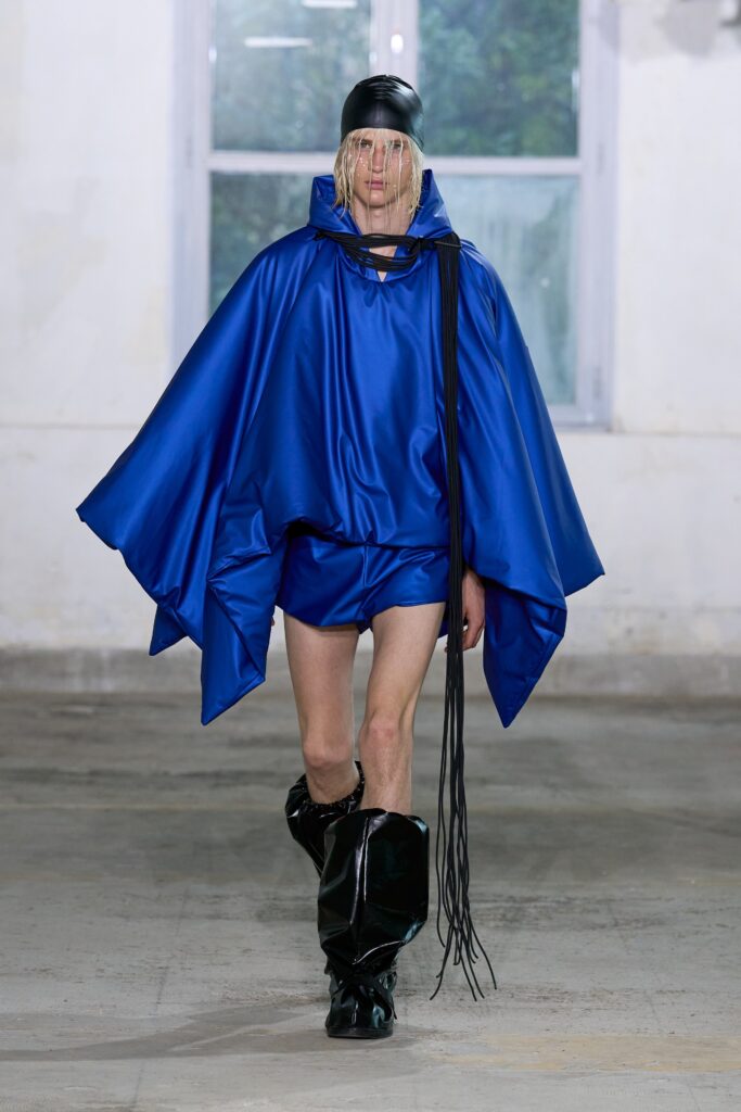 A relaxed blue silk poncho paired with shorts, featuring an asymmetric design.