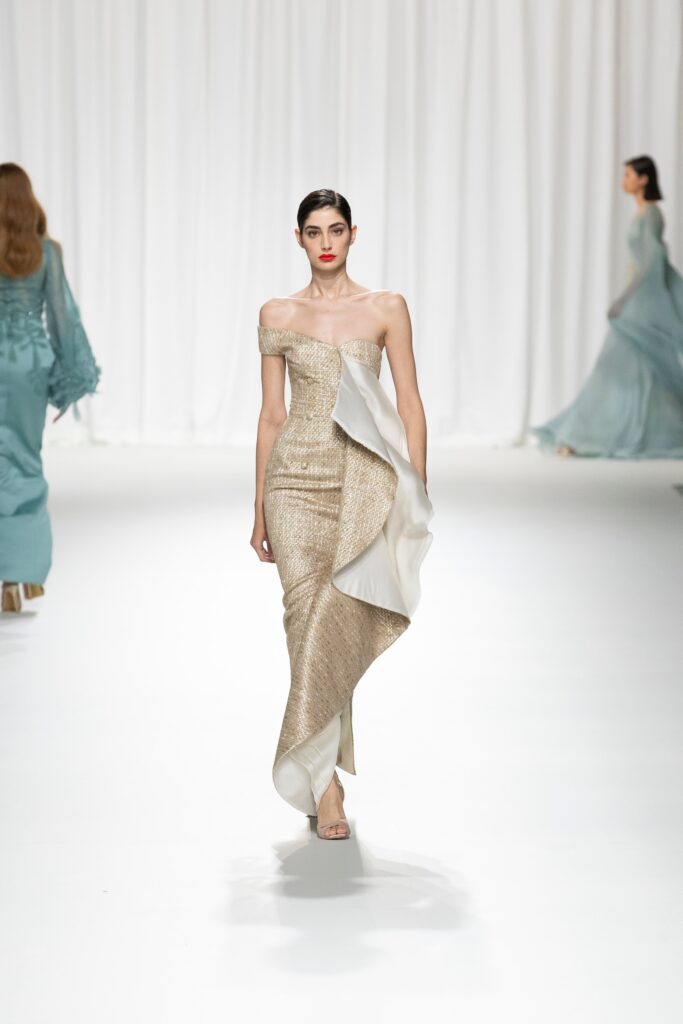 A fitted gold silk strapless gown with an asymmetric design detail.