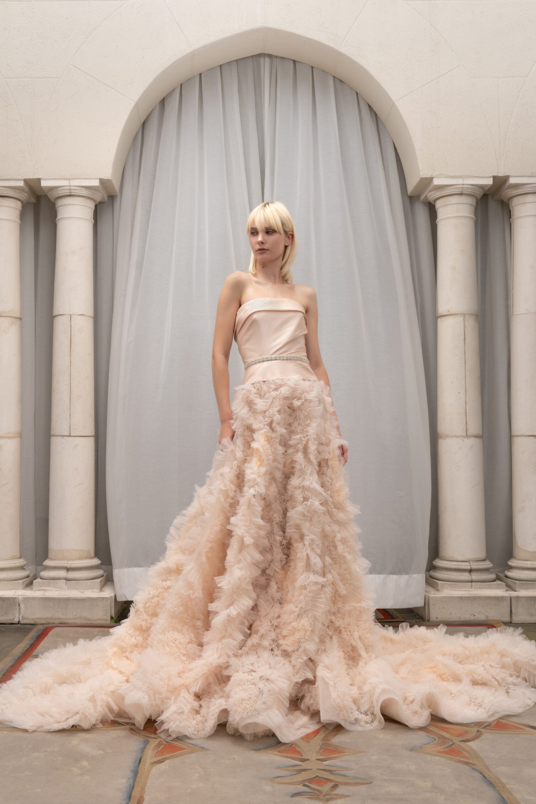 A fitted beige silk strapless gown featuring a ruffled design for a dramatic effect.