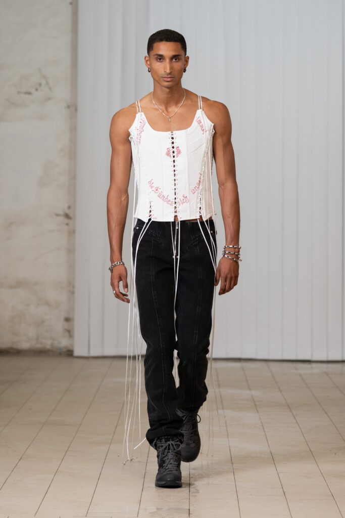 A fitted white top with unique detailing paired with black denim pants for a stylish look.