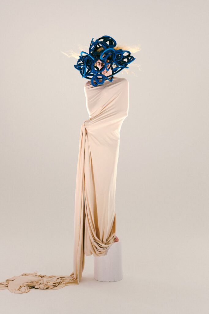 A draped beige silk sleeveless dress that flows elegantly to the floor.