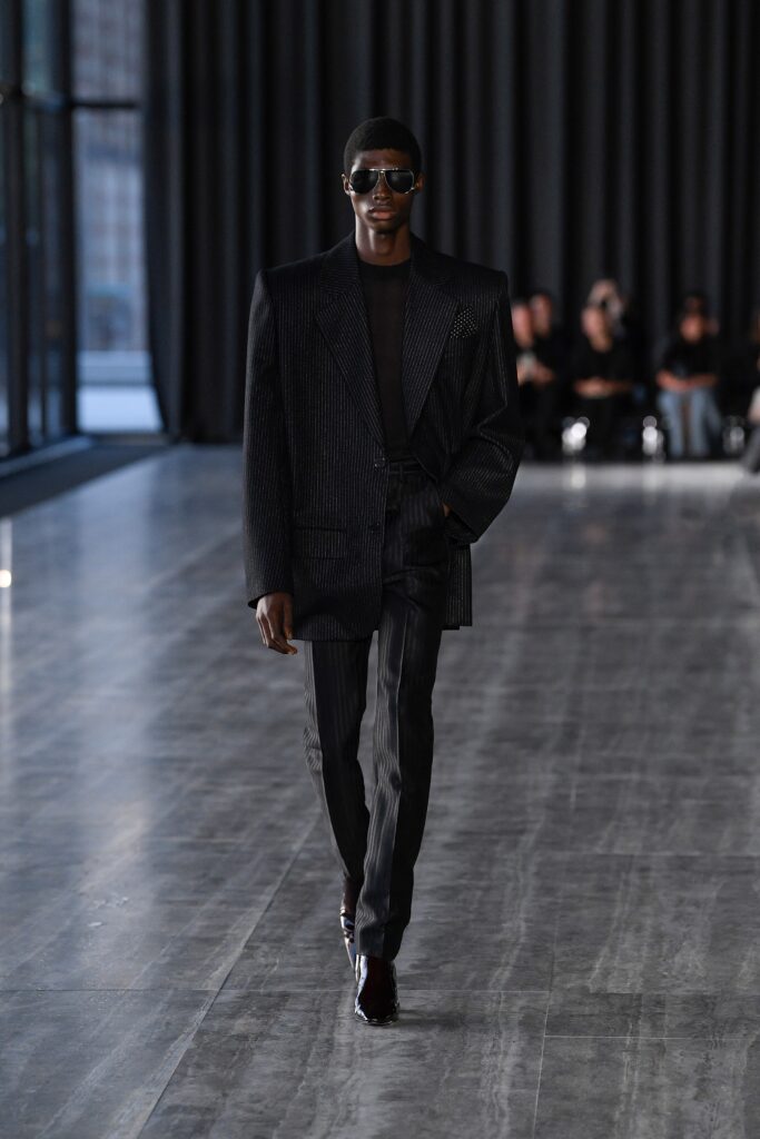 A tailored black wool suit with long sleeves and a collared design featuring stripes.