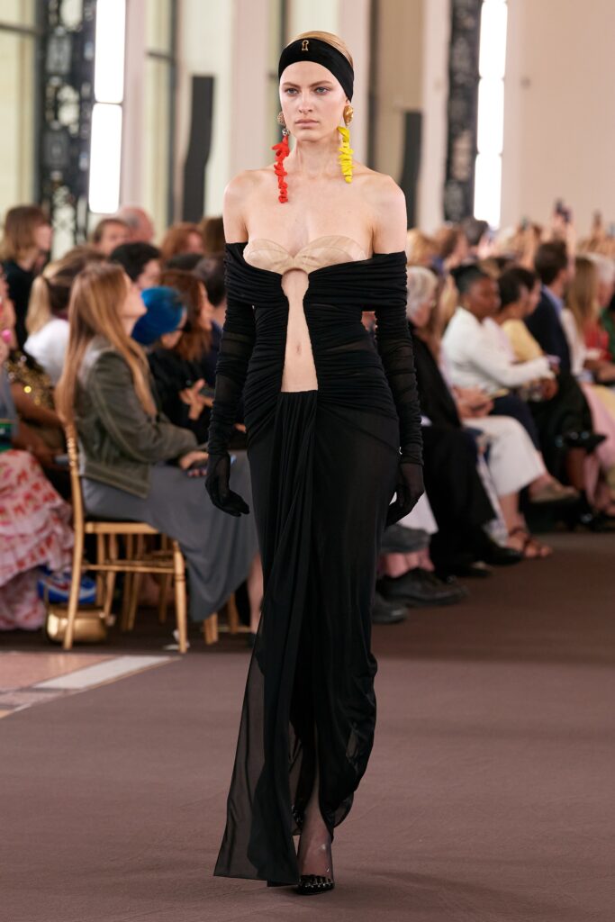 A fitted black silk dress with a V-neckline and asymmetric design details.