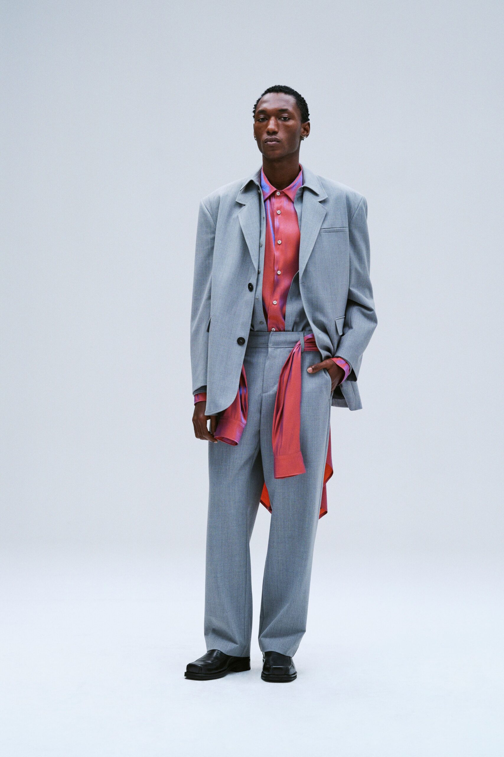 A tailored gray suit paired with a collared red shirt and buttoned details.