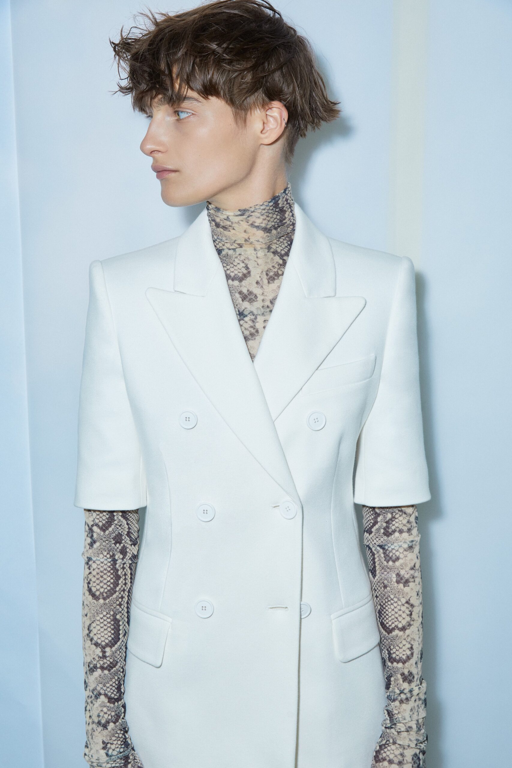 A fitted white blazer paired with a short-sleeve printed top, showcasing a modern silhouette.