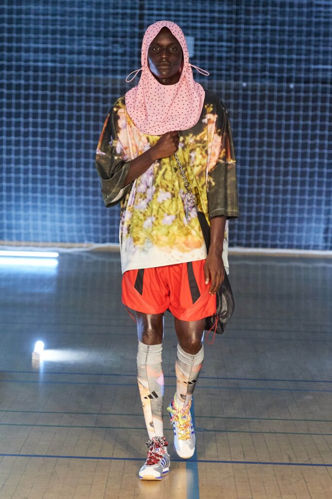 A relaxed multicolor printed top paired with orange shorts for a vibrant streetwear look.