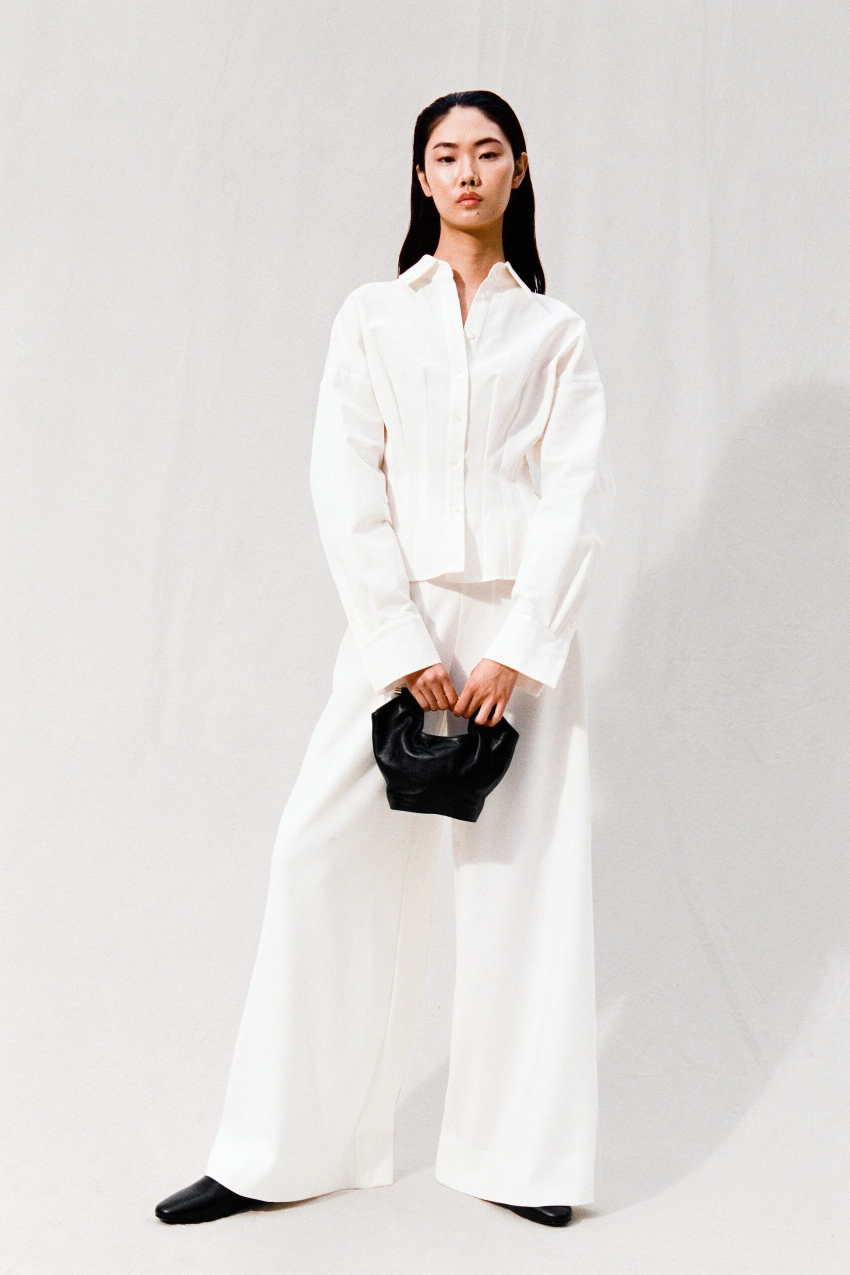 A relaxed white long-sleeve collared shirt paired with wide-leg pants.