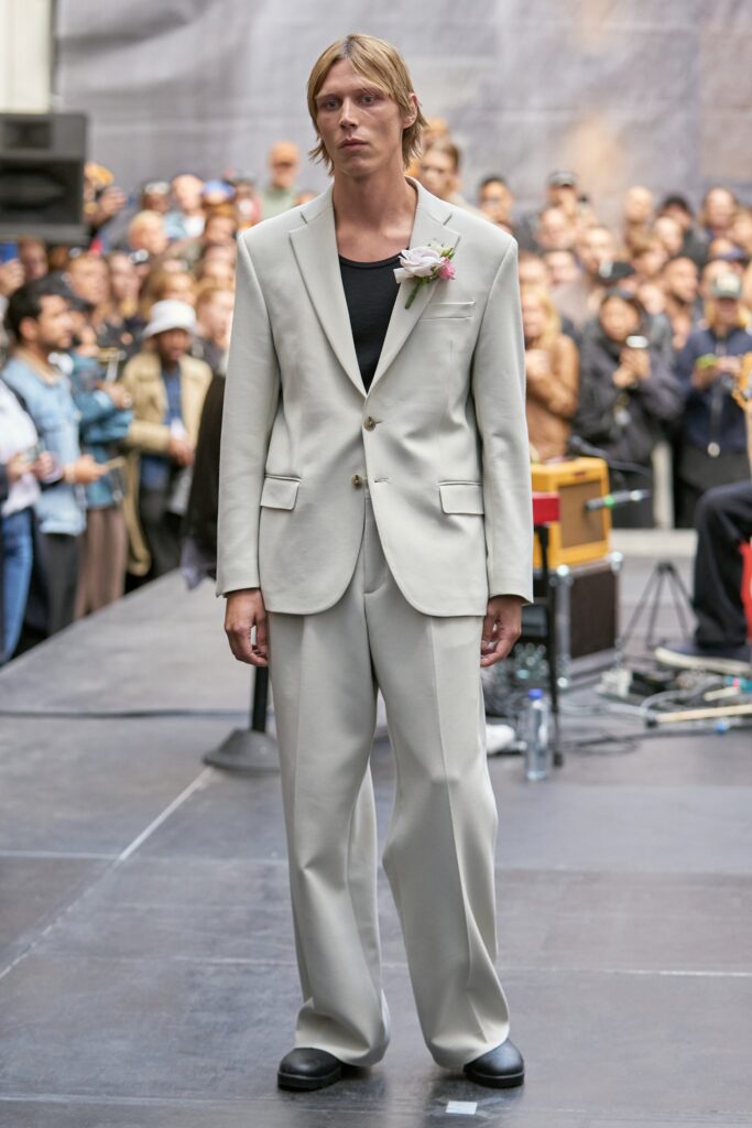 A relaxed beige cotton suit featuring a long-sleeve collared shirt and straight-leg trousers.