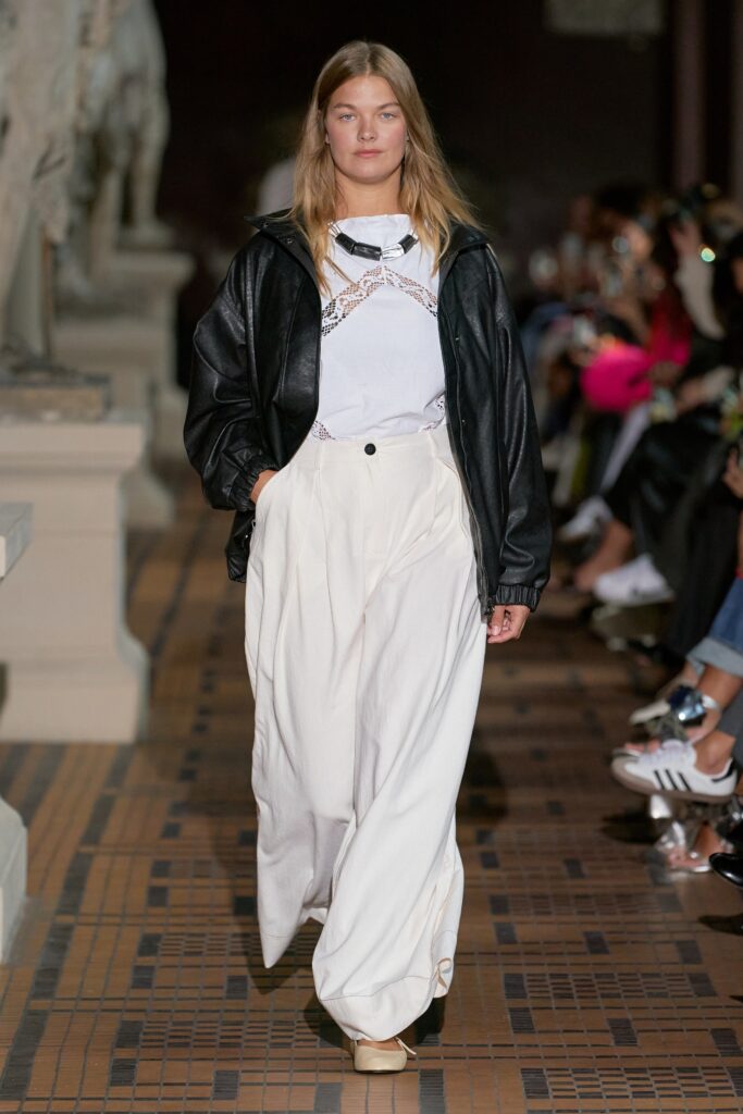 A relaxed black leather jacket paired with white cotton pants featuring a layered design.