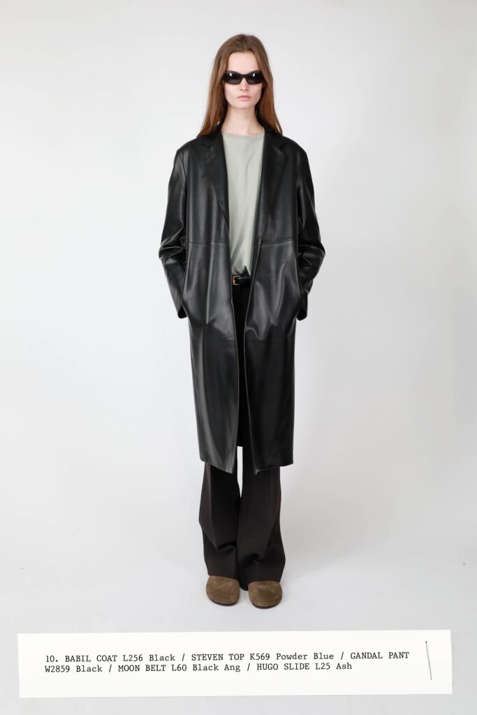 A relaxed black leather coat paired with straight-leg black pants.