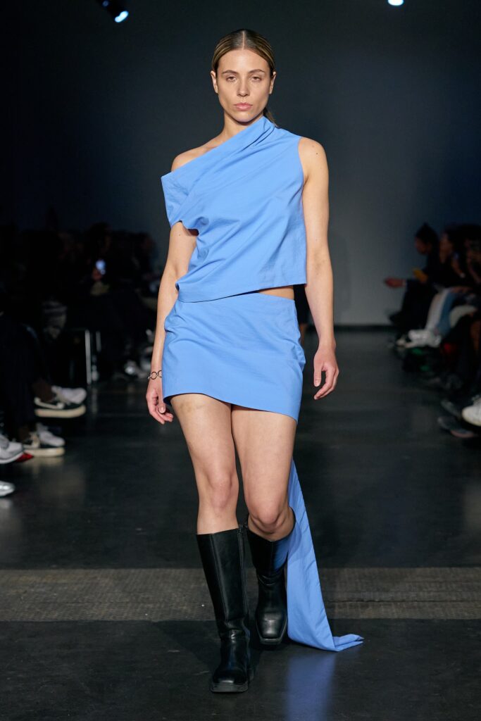 A fitted blue sleeveless top paired with a mini skirt featuring an asymmetric design.