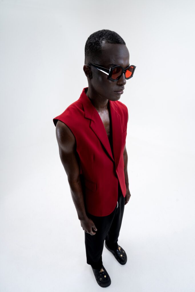 A fitted red sleeveless blazer paired with black pants, showcasing a structured design.