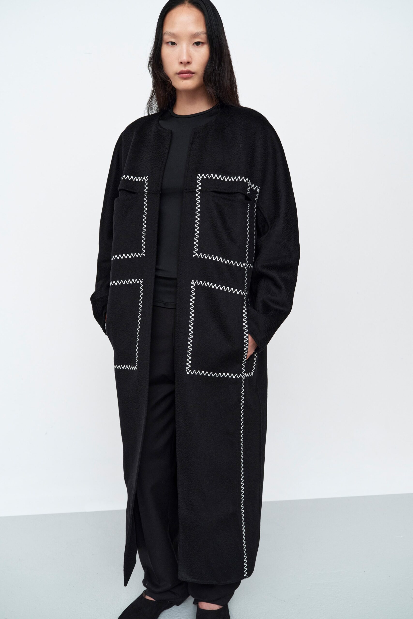 A relaxed black coat with long sleeves paired with matching black pants.