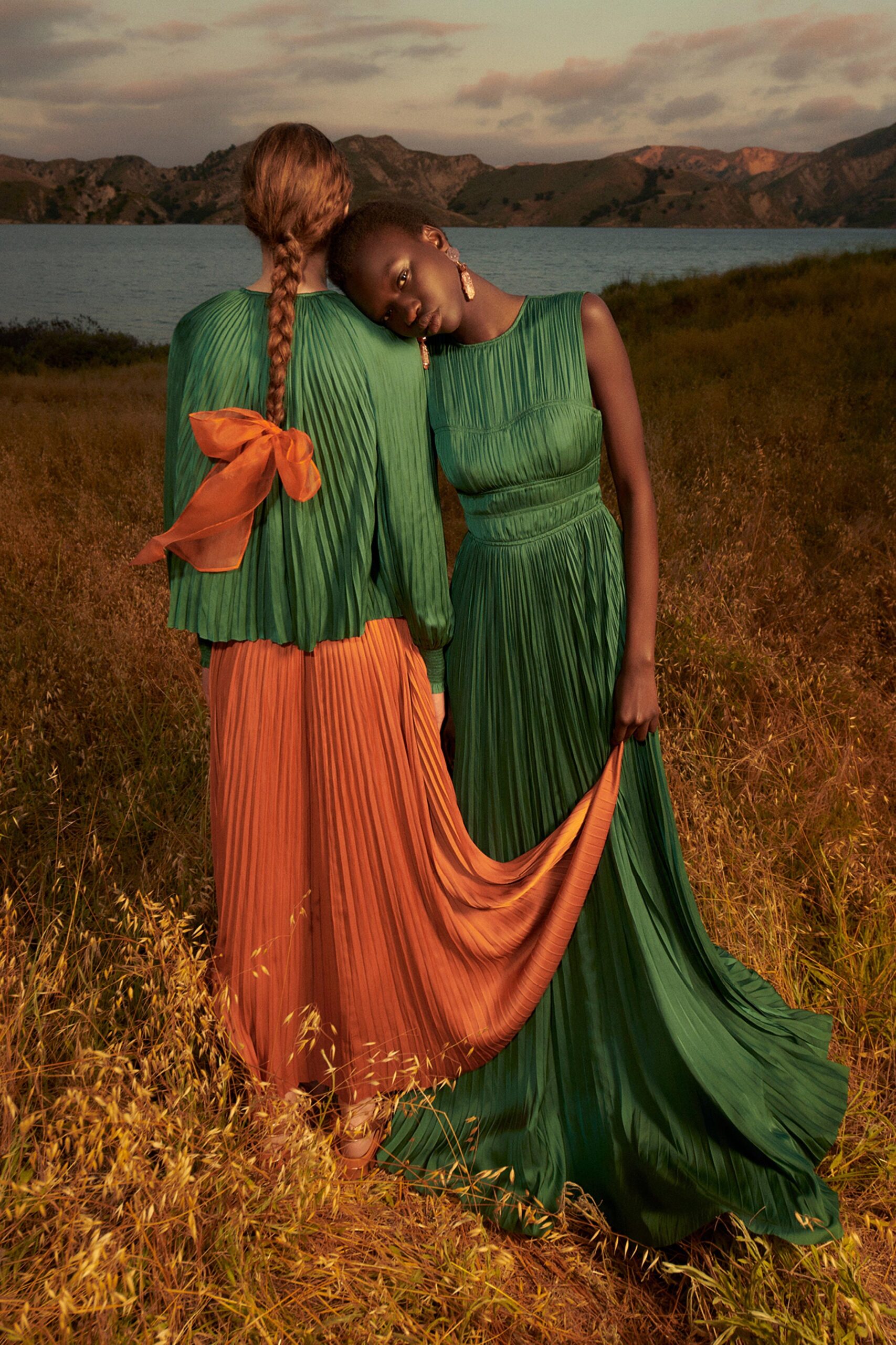 A relaxed green pleated sleeveless dress with a high neckline and tiered design.