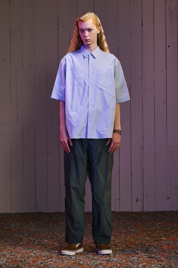 A relaxed blue striped short-sleeve shirt paired with high-waisted gray pants featuring an asymmetric design.