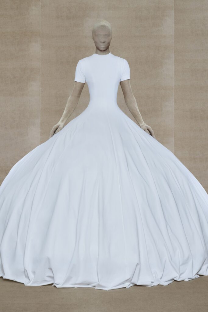 A fitted white short-sleeve dress with a high neckline and flared silhouette.