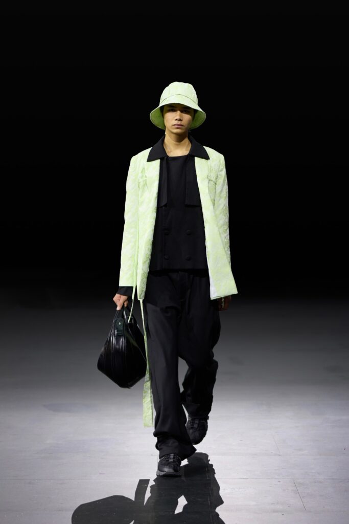 An oversized green coat paired with black pants, creating a stylish and modern look.