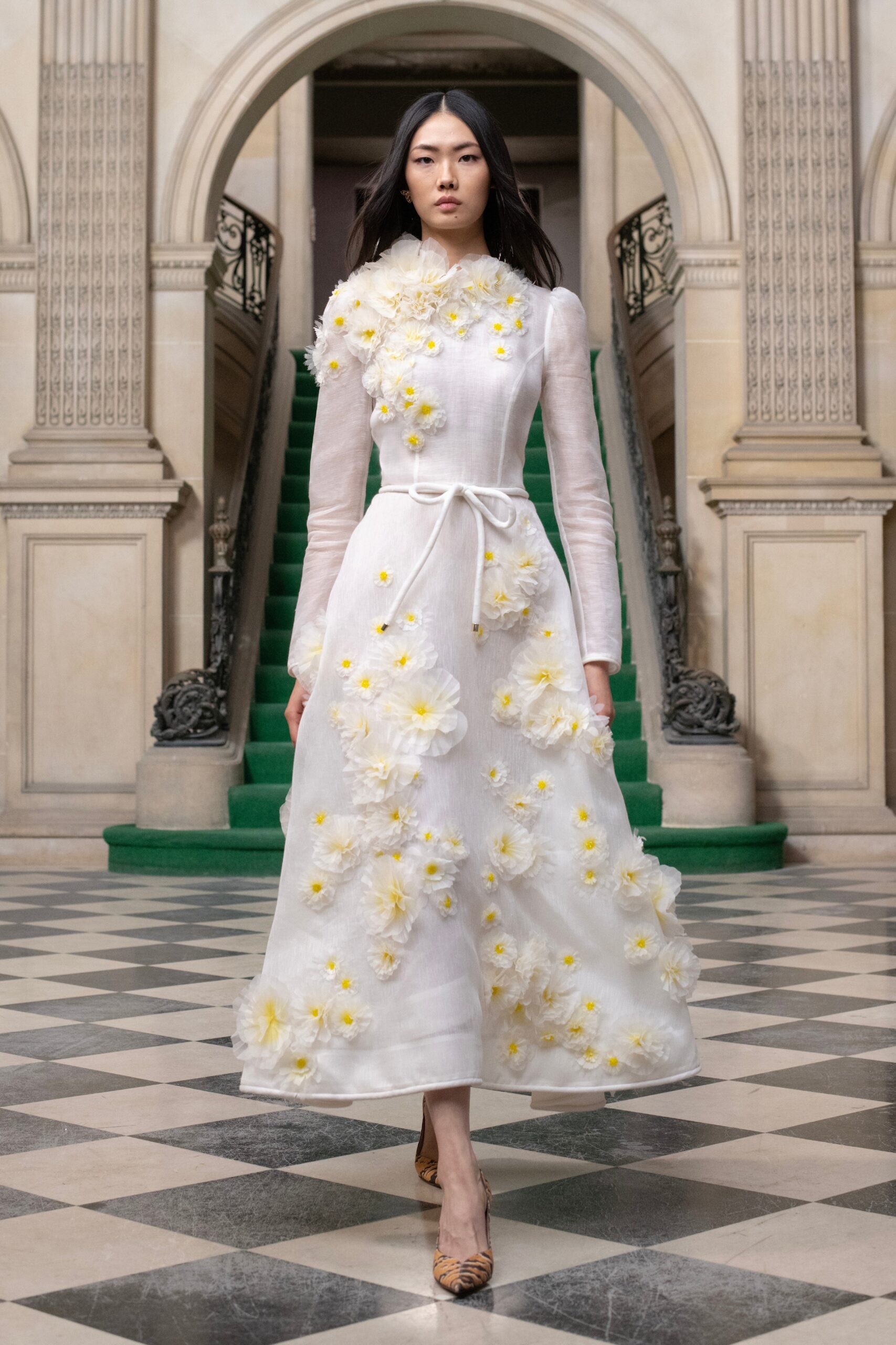 A fitted white dress with long sleeves, a collared neckline, and floral embellishments.