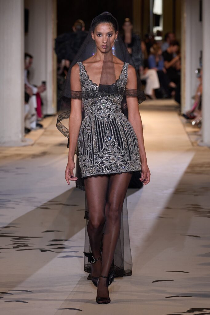 A fitted black silk sleeveless dress with a V-neckline and intricate embroidery.