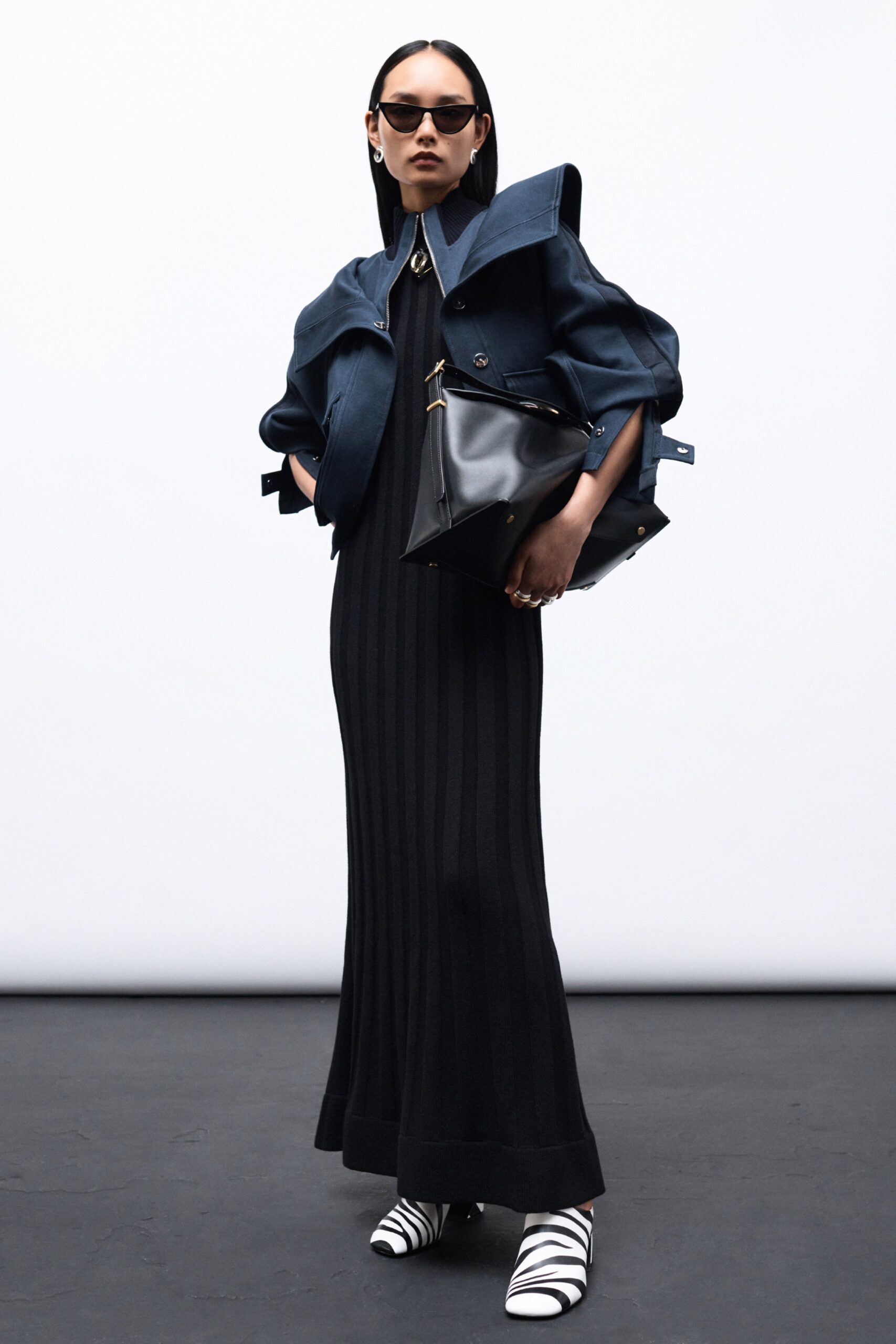 A fitted black striped dress paired with a blue jacket and stylish accessories.