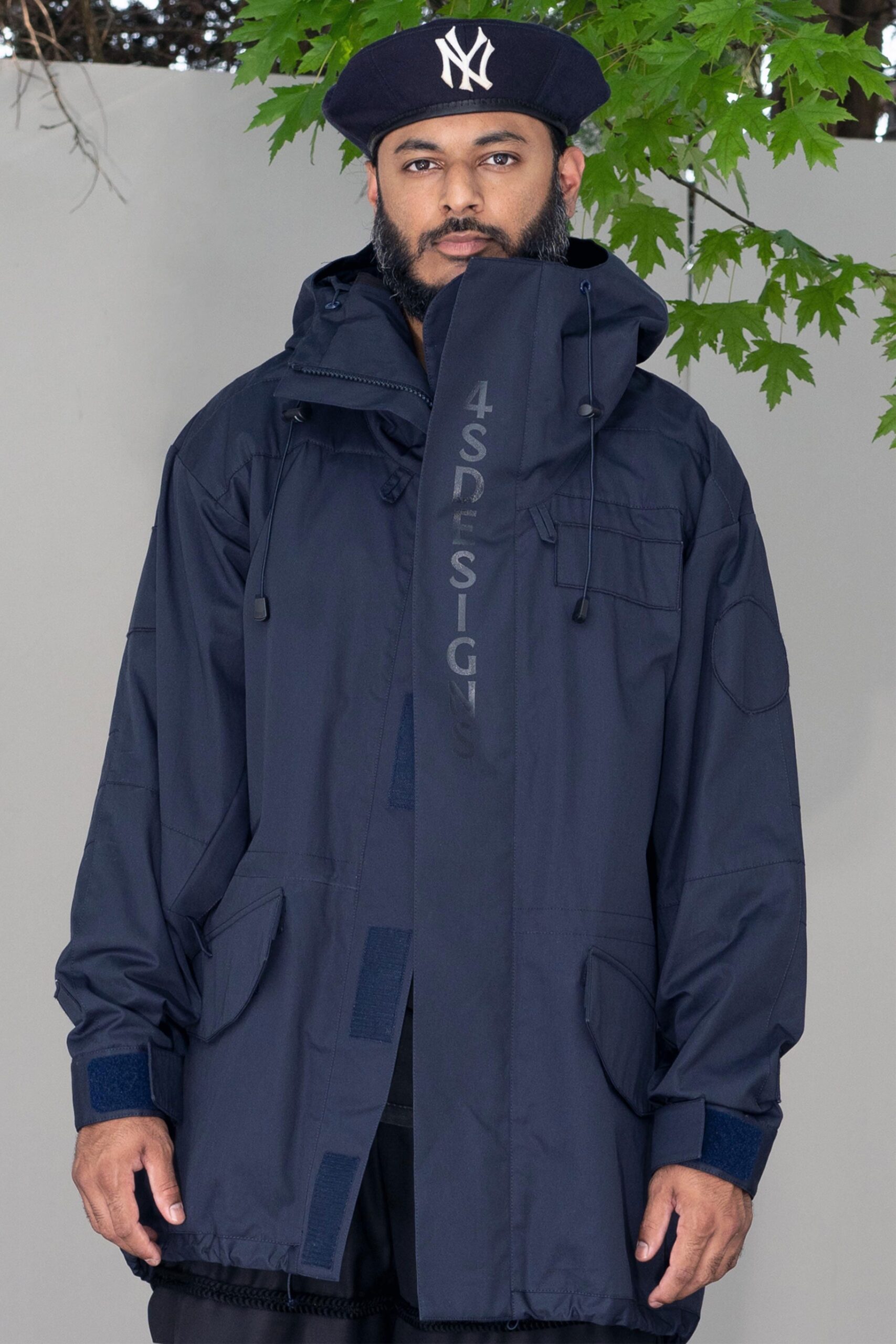 A relaxed navy cotton jacket with a hood and zippered details.
