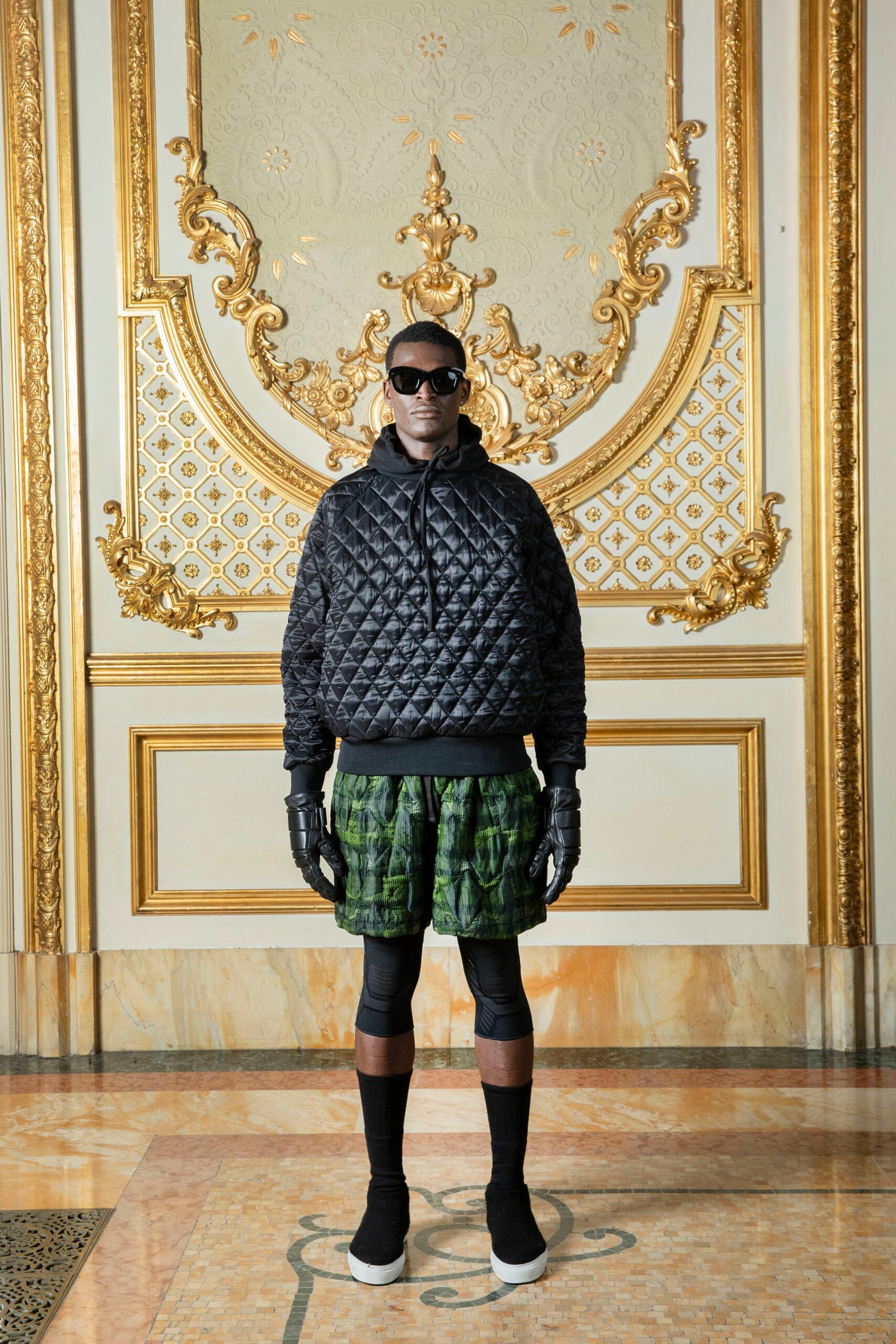 A relaxed black hoodie paired with green printed shorts for a stylish casual look.