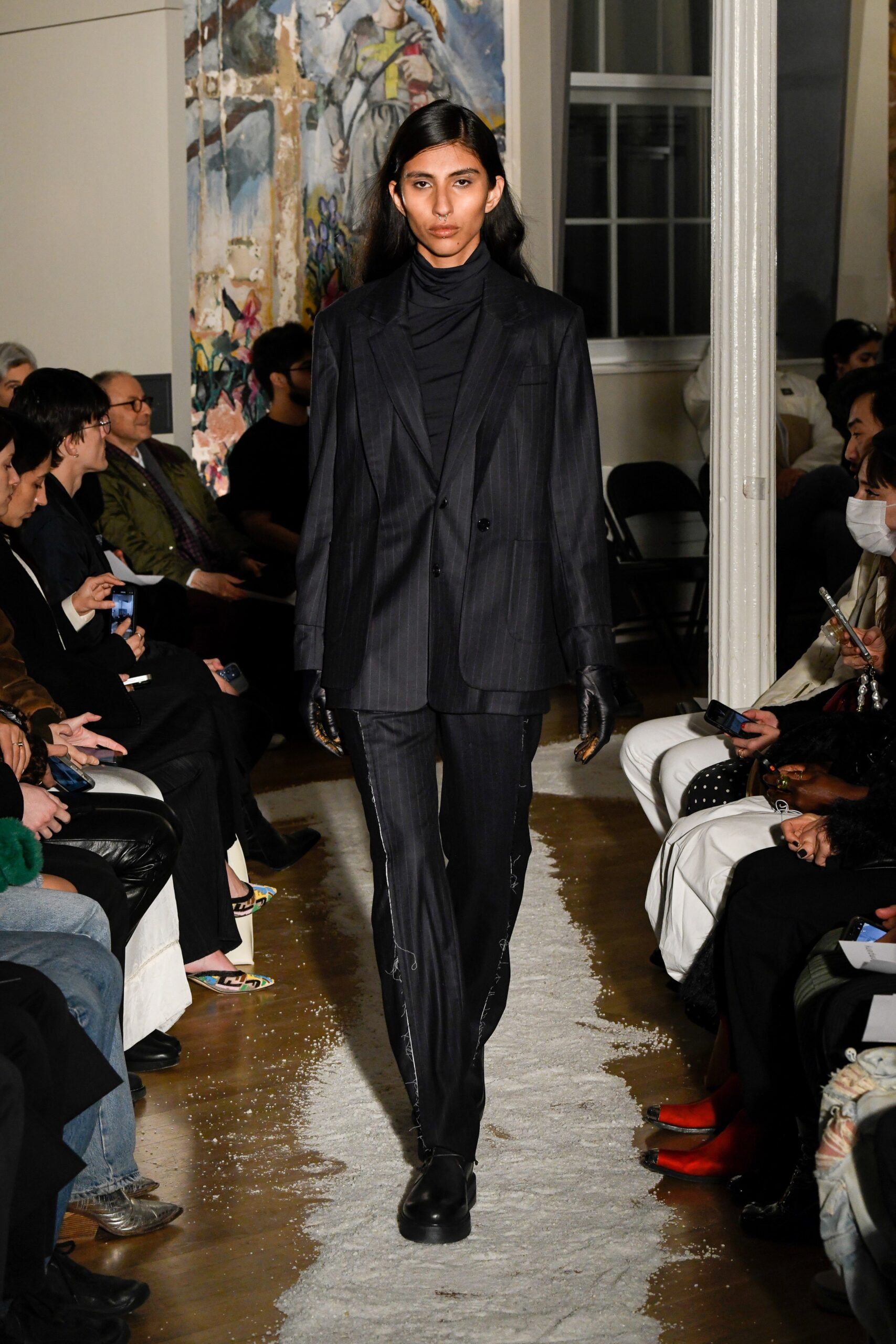 A fitted black wool suit with long sleeves and a collared design featuring a striped pattern.