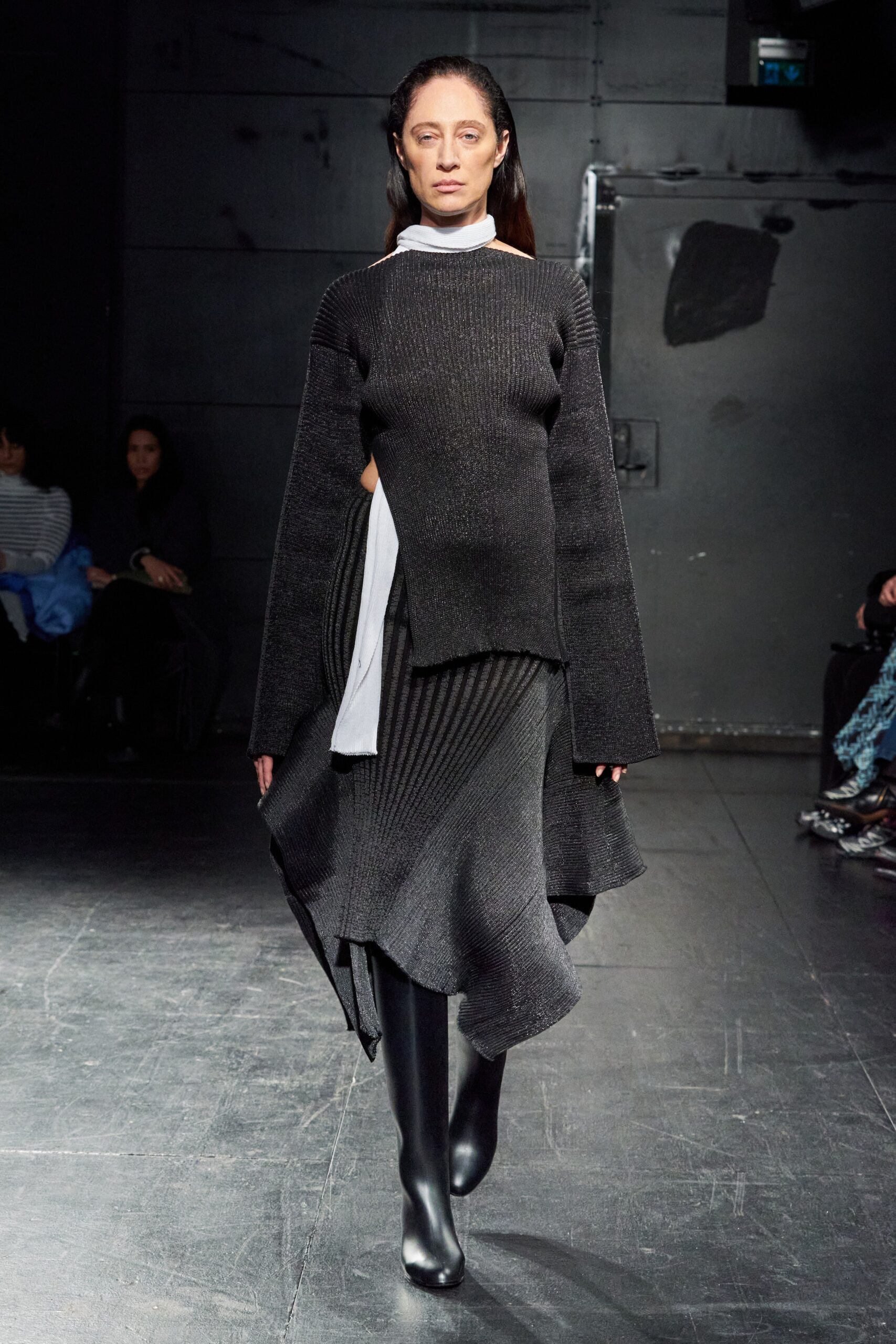 A relaxed black wool dress with long sleeves, high neckline, and an asymmetric layered design.