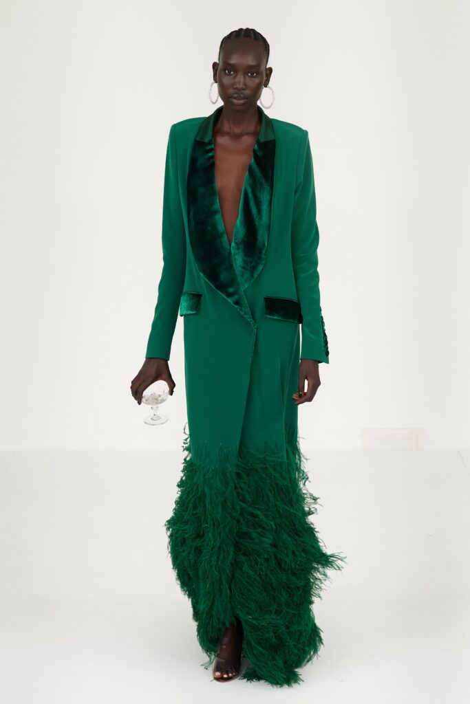 A fitted green velvet long-sleeve dress with a V-neckline and fringed detailing.