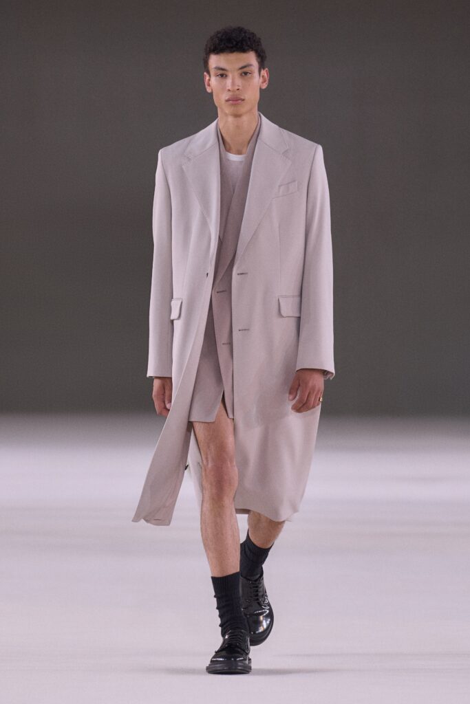 A relaxed beige cotton coat with a collared neckline and layered design details.