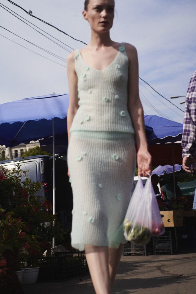 A fitted green knitted dress with a sleeveless design and embroidered details.