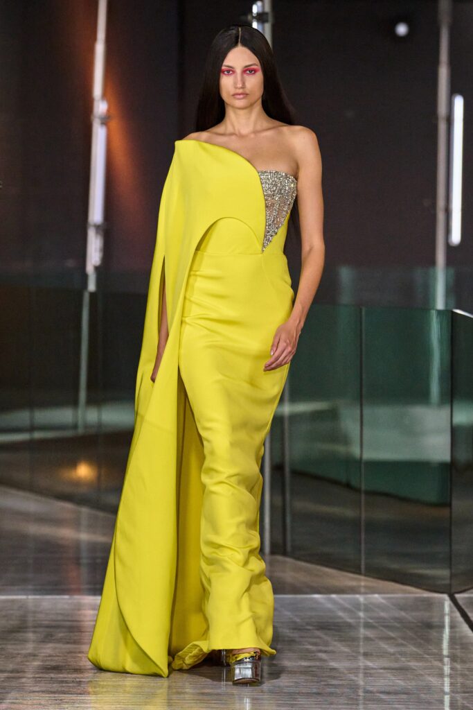 A fitted yellow strapless gown with an asymmetric design and elegant silhouette.