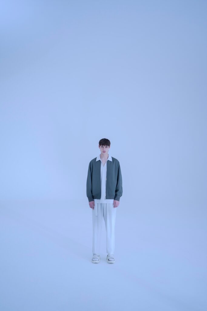 A relaxed gray cotton jacket paired with white straight-leg pants and a collared shirt.