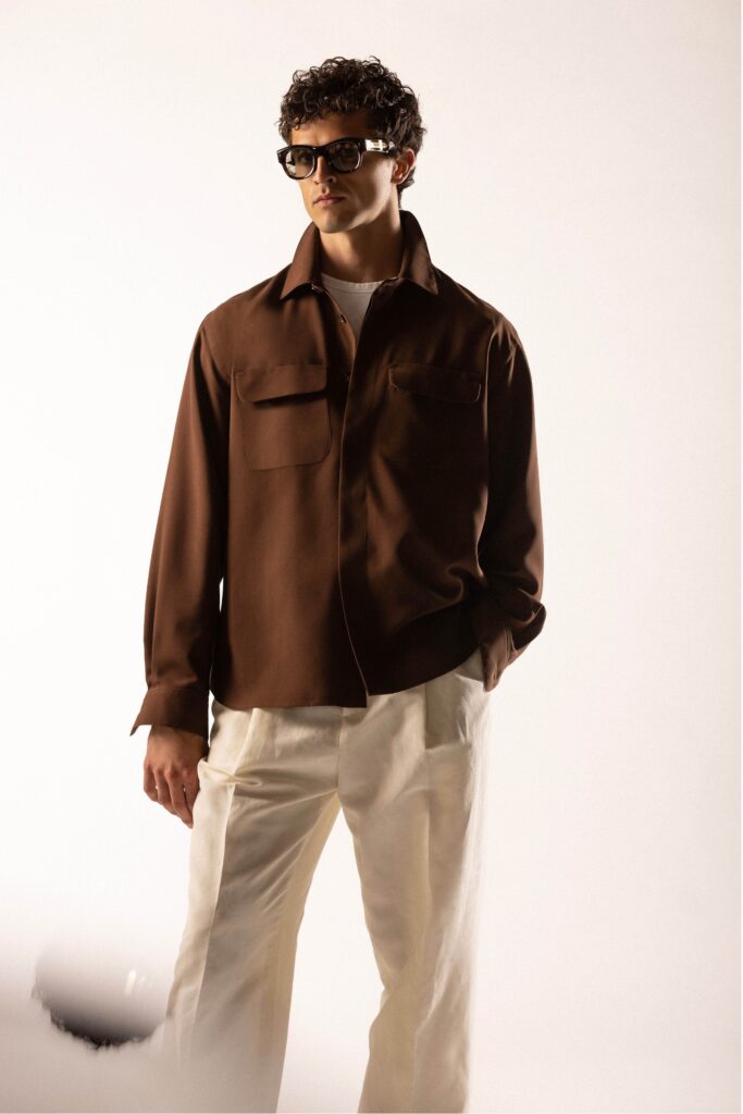 A relaxed brown cotton long-sleeve shirt paired with white pants featuring a buttoned design.