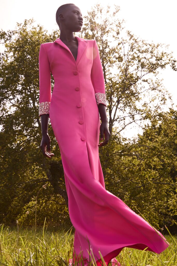 A fitted pink silk dress with long sleeves, a collared neckline, and a buttoned design.