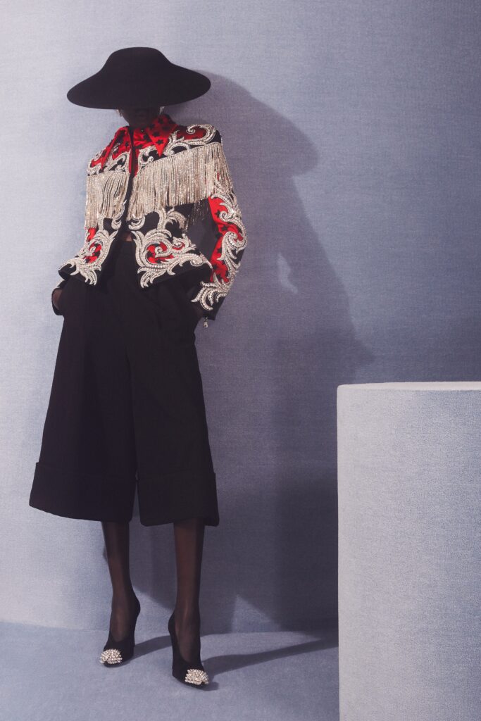 A relaxed black jacket with red embroidery and fringes paired with matching pants.