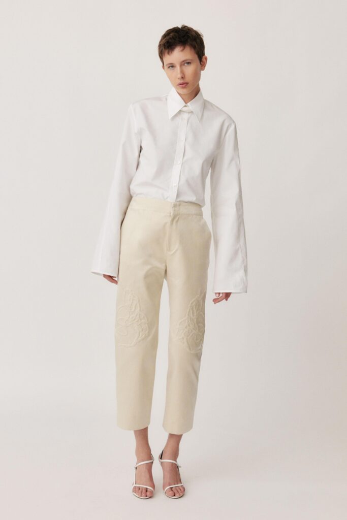 A relaxed white cotton long-sleeve shirt with a collared neckline paired with beige embroidered pants.