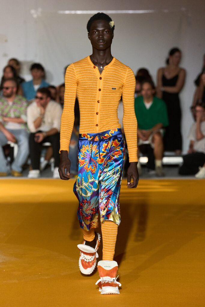 A fitted orange striped long-sleeve shirt paired with multicolor flared pants.