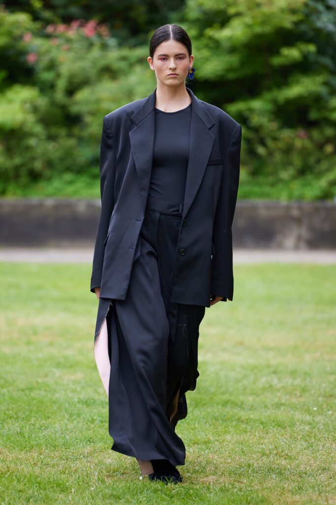 An oversized black jacket paired with asymmetric black pants, creating a bold fashion statement.