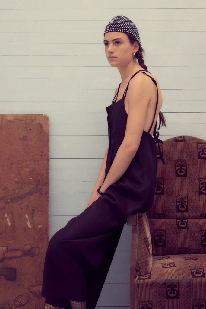 A relaxed black cotton sleeveless jumpsuit with a backless design and wide-leg silhouette.