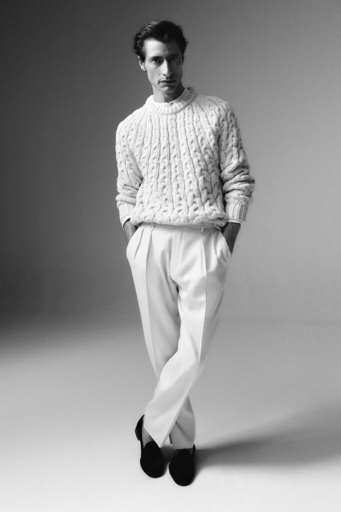 A relaxed white wool cable-knit sweater paired with tailored pants for a sophisticated look.