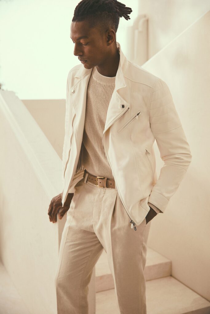 A fitted white leather jacket paired with beige cotton pants, featuring a collared design and zippered detail.