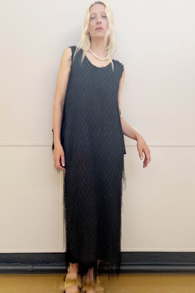 A relaxed black sheer sleeveless dress with a high neckline and layered design.