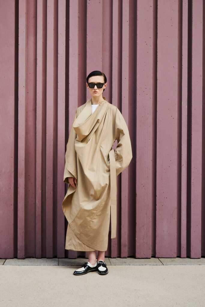 A relaxed beige long-sleeve dress with a high neckline and asymmetric design.