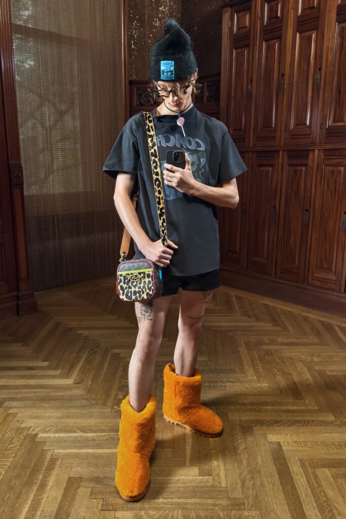 A relaxed black t-shirt with printed design paired with orange shorts.