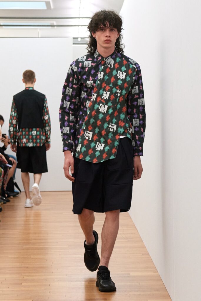 A relaxed-fit multicolor printed shirt with long sleeves paired with black shorts.